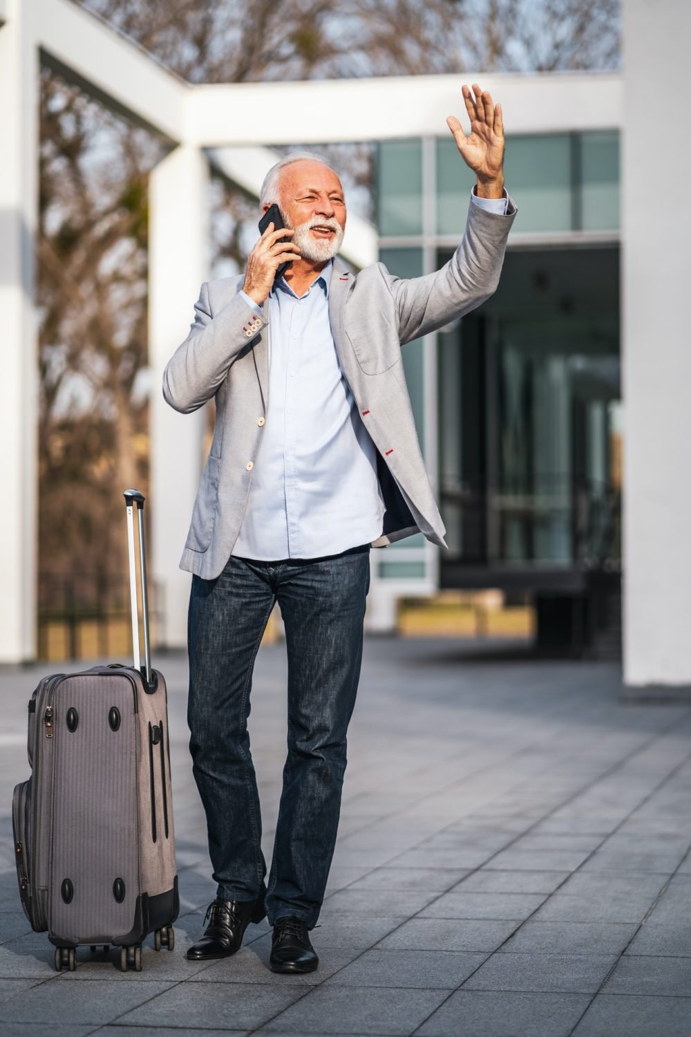 senior man calling a taxi with luggage bradford